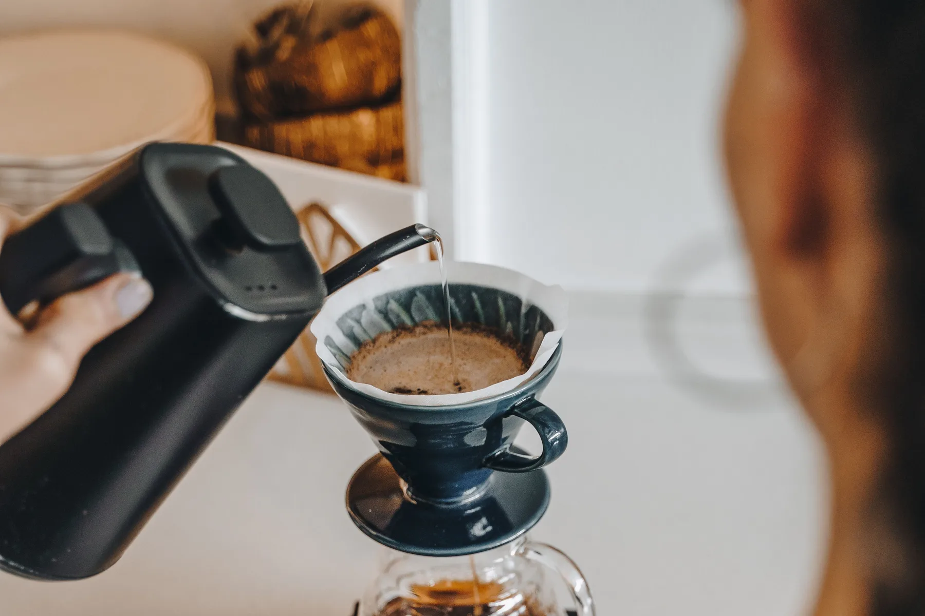 A controlled kettle pour over a seated coffee filter and dripper