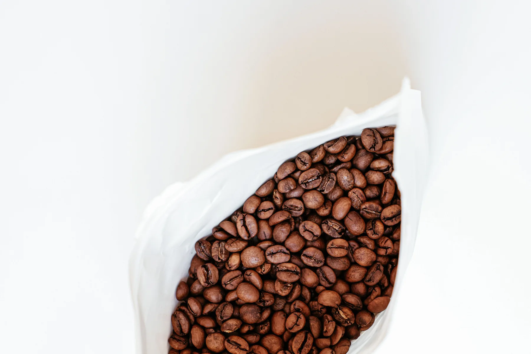 Whole roasted coffee beans in a plain unbranded bag